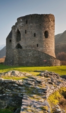 Ruins of a castle in the countryside surrounded by mountains. 