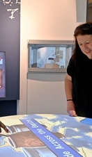 Three people looking at an interactive exhibit in a museum of Roman Britain