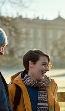Young couple standing by a wooden fence. Manor in background
