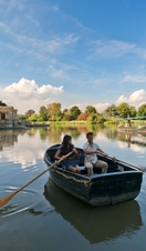 A man and woman in a rowing boat, rowing in still waters