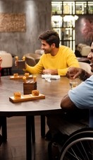 Group of friends, one wheelchair user, sat around a table