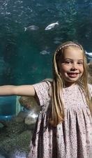 A child standing in front of fish in an aquarium