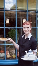 Waitress holding tray with tea and cake standing