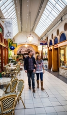 A couple walking through an indoor market, past a café
