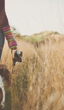 Woman and dog walking through grass