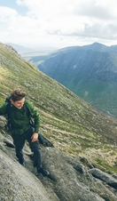 Man climbing to mountain summit, Scotland
