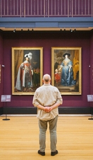 Rear view of man standing looking at portraits in a gallery