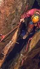A man exploring through a cave system at Cornwall Underground Adventures