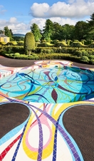 Ground pool sculpture in the landscape at Jupiter Artland with house and topiary gardens in distance