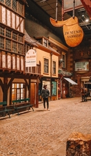 A man standing in an old street, under shop signs