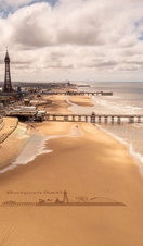 Landscape shot of a sandy beach with a pier and tower.