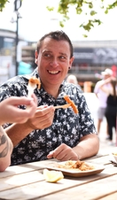 A group of men eating food at a table at the International Food and Drink Festival in Cardiff, Wales