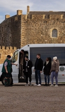 People arriving from a tour bus to visit a castle. 