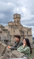 A man and a woman look out to a view from a castle
