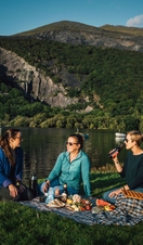 Friends having a picnic in grassland by a glacially formed lake.