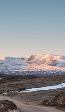 A rugged road leading through the valley to snow covered mountains in the distance
