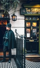 A man in an old style police uniform standing outside