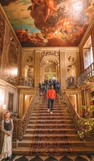 Group of people walking down stairs under a painted ceiling