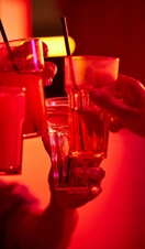 Cropped image of male and female friends toasting drink glasses at bowling alley.