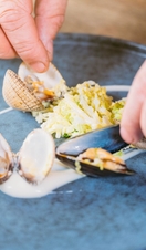 Close up of chef dressing plate with clams and scallops