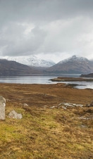 Man standing on boulder looking out over landscape with mountains in distance
