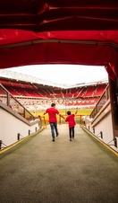 A man and boy in stadium tunnel looking out to pitch 