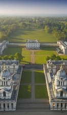 Aerial view of a massive mansion and manicured gardens.
