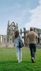 A man and woman walking towards a heritage Abbey building