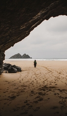 A woman walks through a cave on a beach