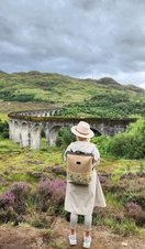 A woman standing in the countryside overlooking a viaduct. 
