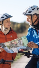 A man and a woman look at a trail map while riding e-bikes at Dalby Forest.