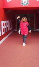 A woman posing while on a stadium tour of Anfield, Liverpool.