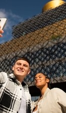 People posing for selfie in front of the Birmingham Library