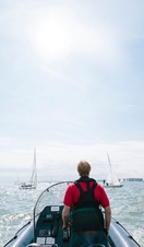 Man steering a power boat during a sailing race with yachts either side