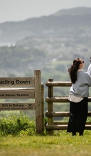 A man and a woman stand at gate with the town and sea beyond