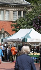 People visiting an outoor produce market near a historic building.