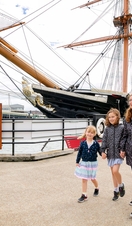 A family walking alongside a ship at a dock