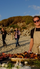 A man posing behind a row of barbeque food at Taste of Scilly Food Festival on Tresco Island