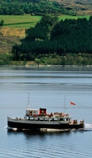 A traditional blue and white pleasure boat with a red and black funnel ferrying visitors on a lake.