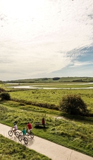 A family cycling along path through the wide open landscape