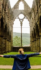 A woman with arms out stretched inside a vacant crumbling church
