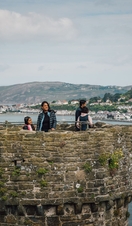 Family on top of a castle enjoying river views with boats docked and hills in the distance