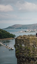 Family on top of a castle enjoying river views with boats docked and hills in the distance
