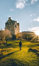 Man walking towards a castle with sun rising in the sky