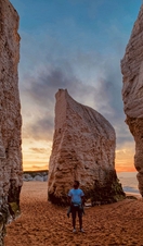 Man standing on beach looking up at cliffs