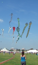 People flying colourful kites against a blue sky