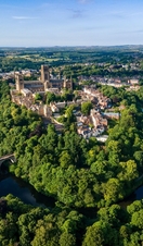 An elevated view of a Cathedral set amongst trees and a river