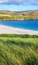 A woman sitting in grass overlooking a spit and fields