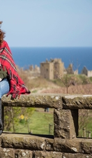 Women holding mugs with hot drinks, sitting on a stone wall