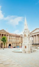 Historical building, with a clock tower, beside a fountain